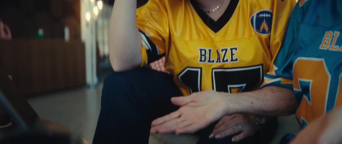 A devoted female football fan wearing a yellow jersey looks down in despair after her team's loss