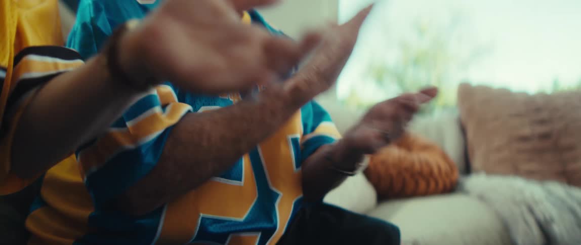 A joyful granddaughter and her elderly grandmother clap in unison, cheering for their favorite football team in slow motion