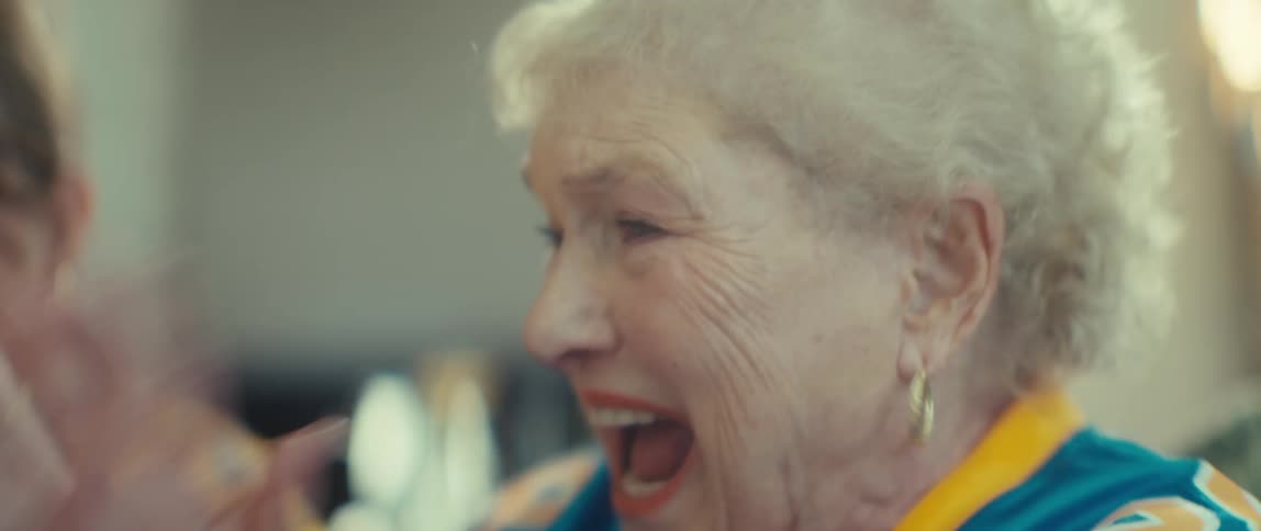 A close-up shot of two female football fans, one young and one elderly, excitedly clapping and cheering for their team in slow motion
