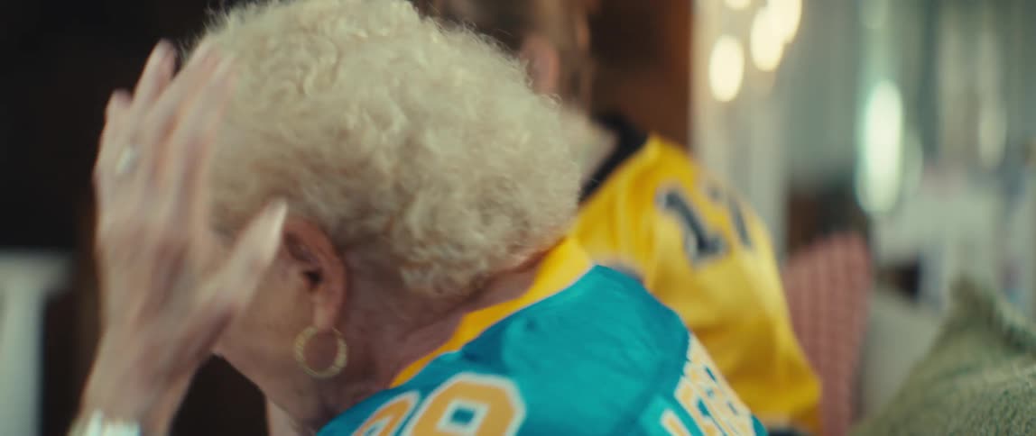 An elderly woman and her friend in team jerseys react with disappointment as they watch their favorite sports team lose the game