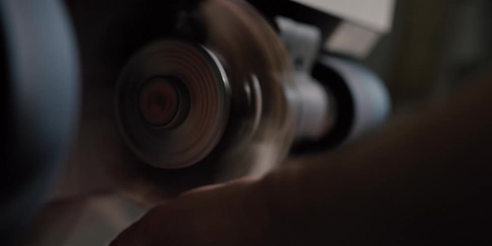 A skilled shoemaker carefully polishes the red heel of a shoe on a finishing machine in a workshop
