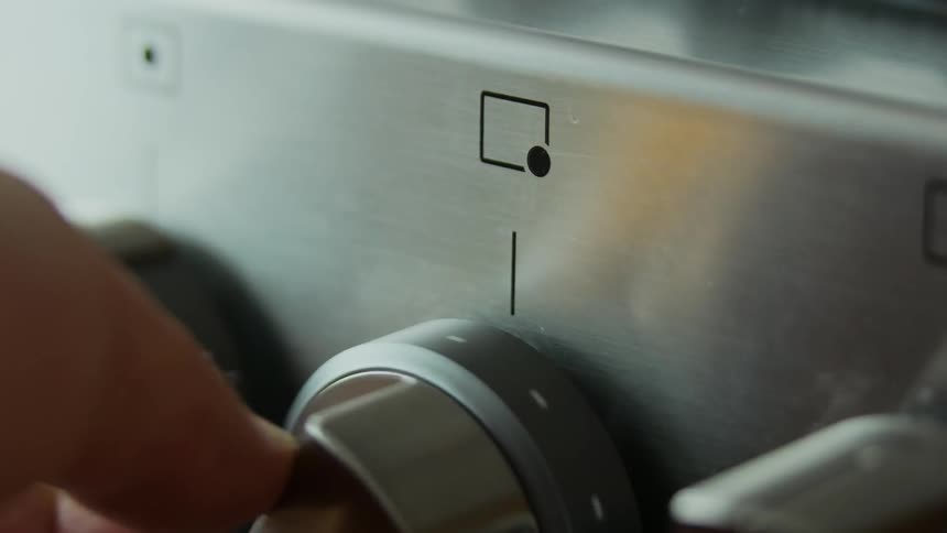 Hand turning a knob on a stove