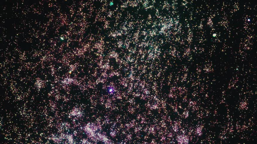 Countless multi-colored particles twinkle and expand, creating a cosmic nebula effect against a black backdrop