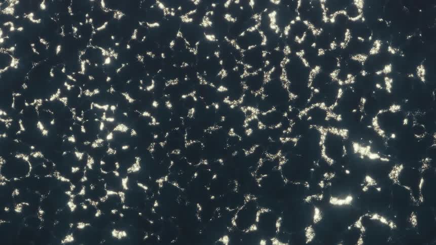 An abstract top-down view of shimmering glitter particles slowly swirling in dark, viscous liquid