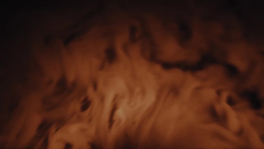 Mysterious amber-colored fog gently rolls and swirls across a black backdrop