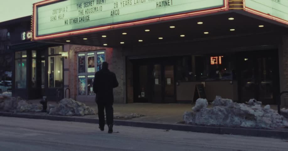 A man jogs toward a movie theater on a cold winter evening in slow motion