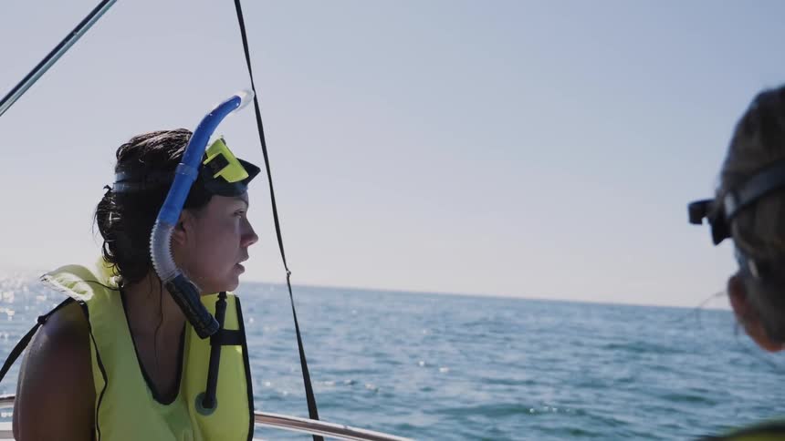 A woman has scuba gear on riding in a boat