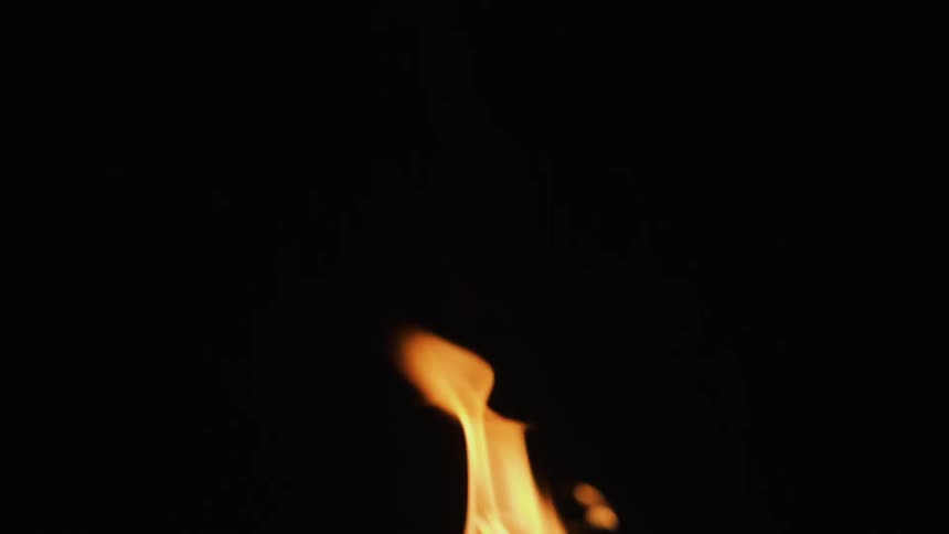 A flame burns in the black night
