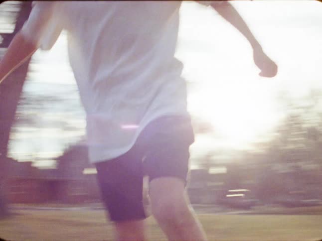 Dreamy, motion-blurred 8mm footage follows two young boys as they energetically play soccer together in a park