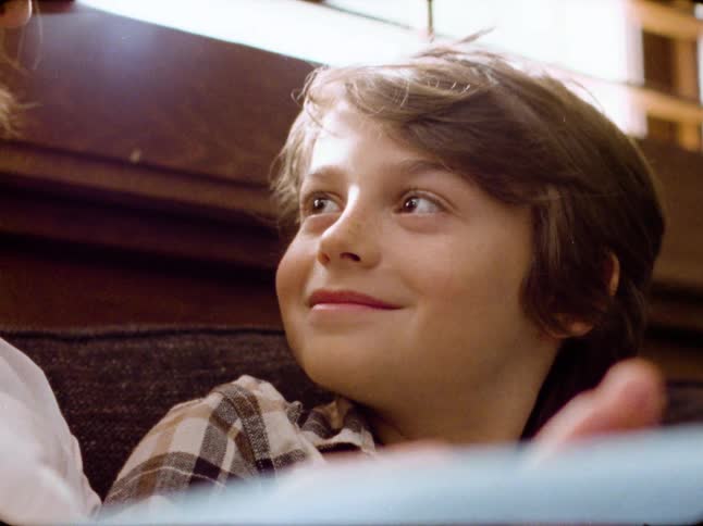Archival footage captures a heartwarming close-up of a young boy smiling affectionately while looking up at someone