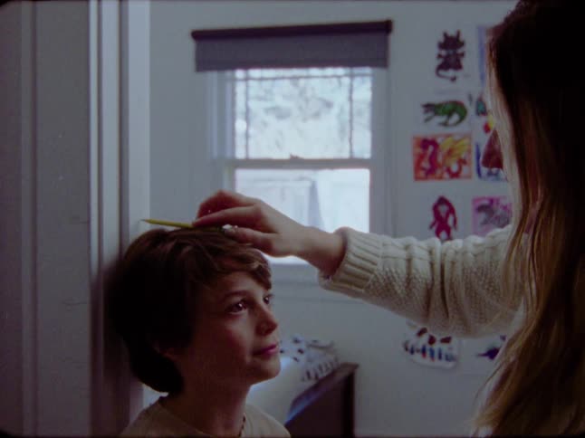 A mother marks her growing son's height on a door frame in his bedroom in this vintage-style footage