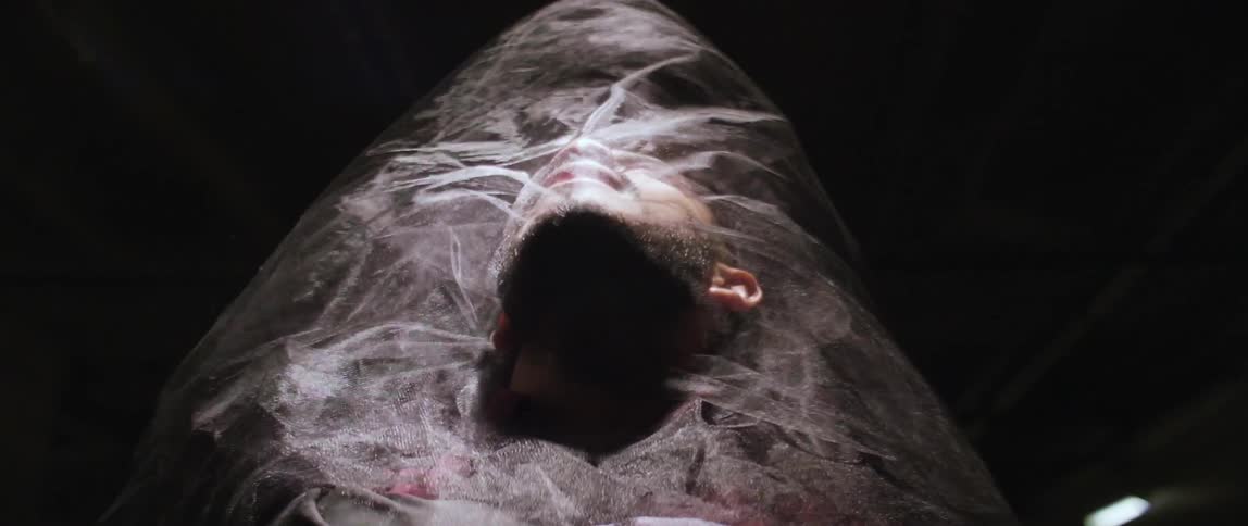 Guy facing a light with sheer fabric floating around him