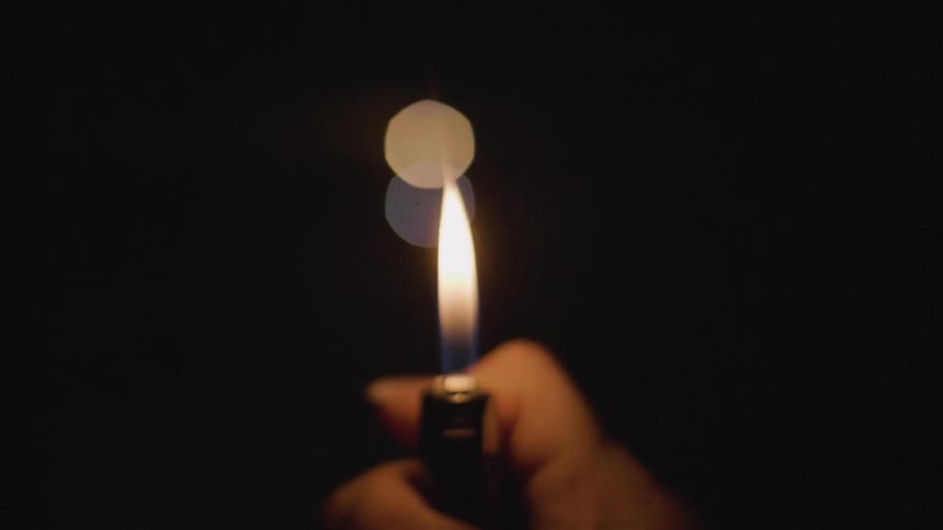 A lighter is lit in a dark room