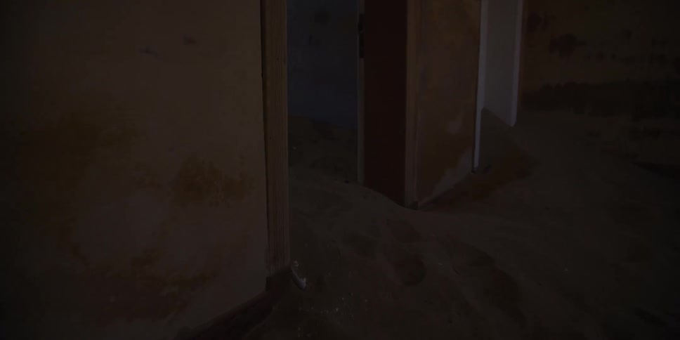 Slowly moving through the dark, eerie rooms of an abandoned desert home that have been completely filled with sand