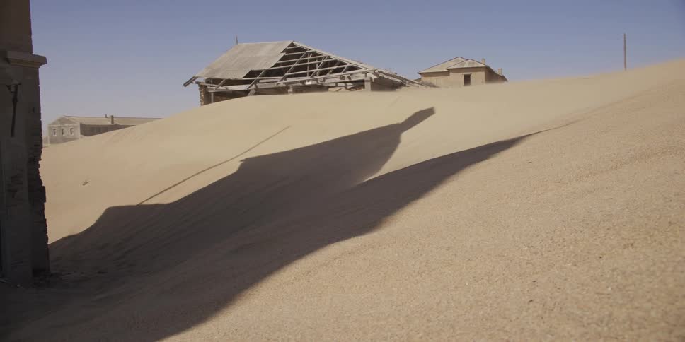 Desolate ghost town in the desert with sand dunes slowly swallowing the abandoned and decaying buildings