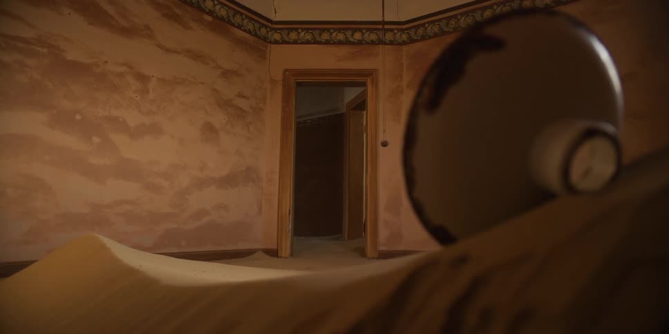 A desolate room in an abandoned house is slowly being reclaimed by the desert sand