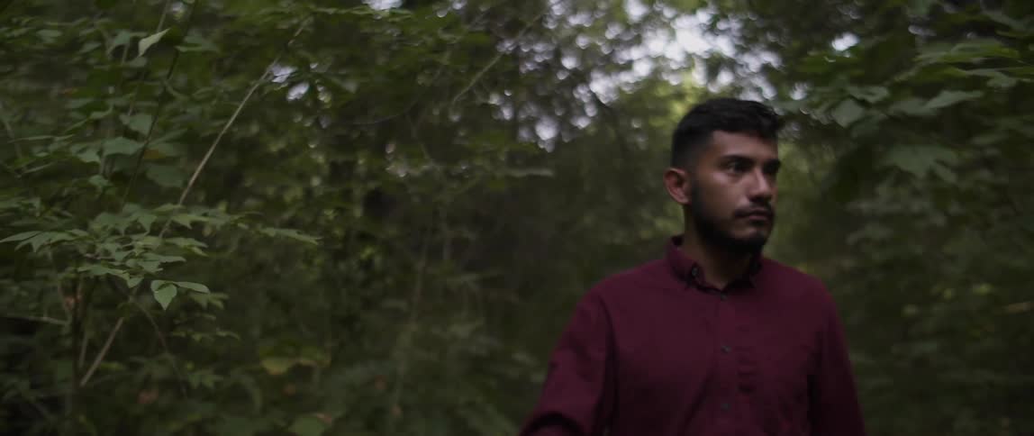A man with a red shirt walks in the forest