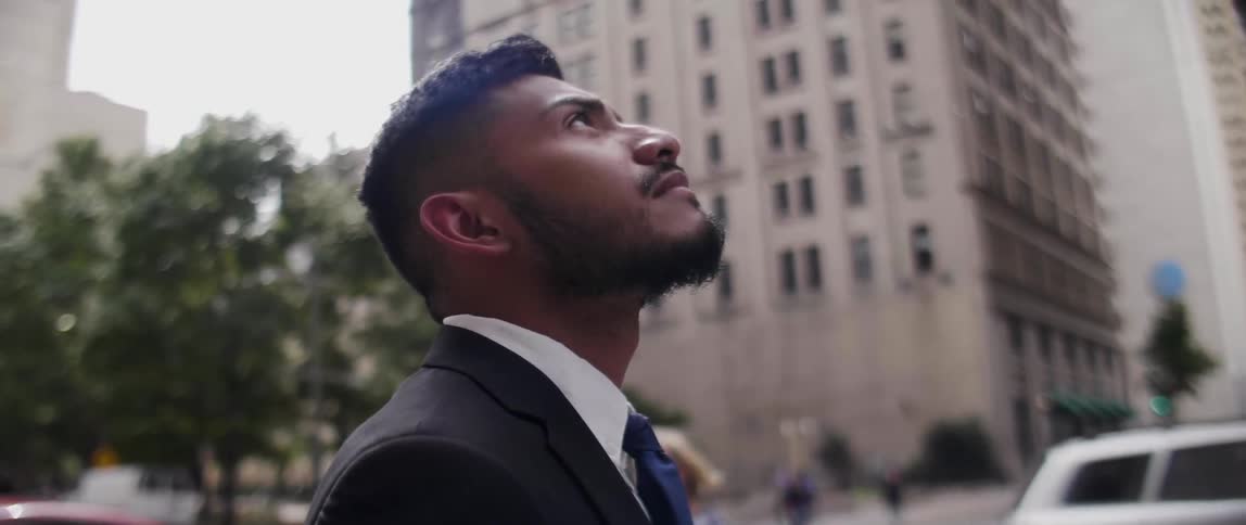 A man looks up at tall city buildings