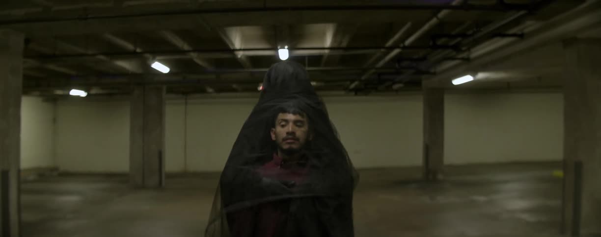 A man is surrounded by a black robe in a lot