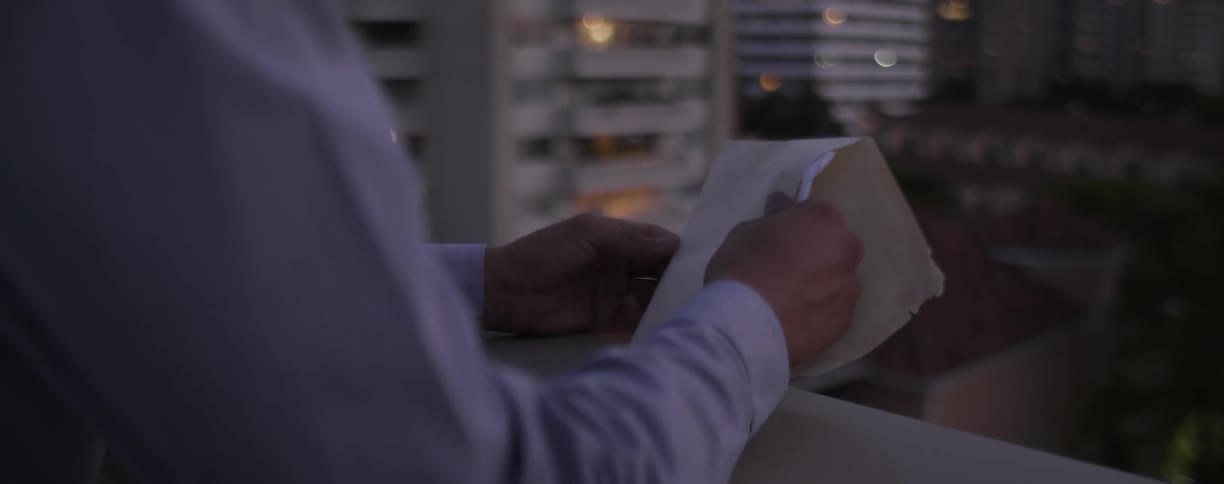Man stands on his balcony and opens a letter