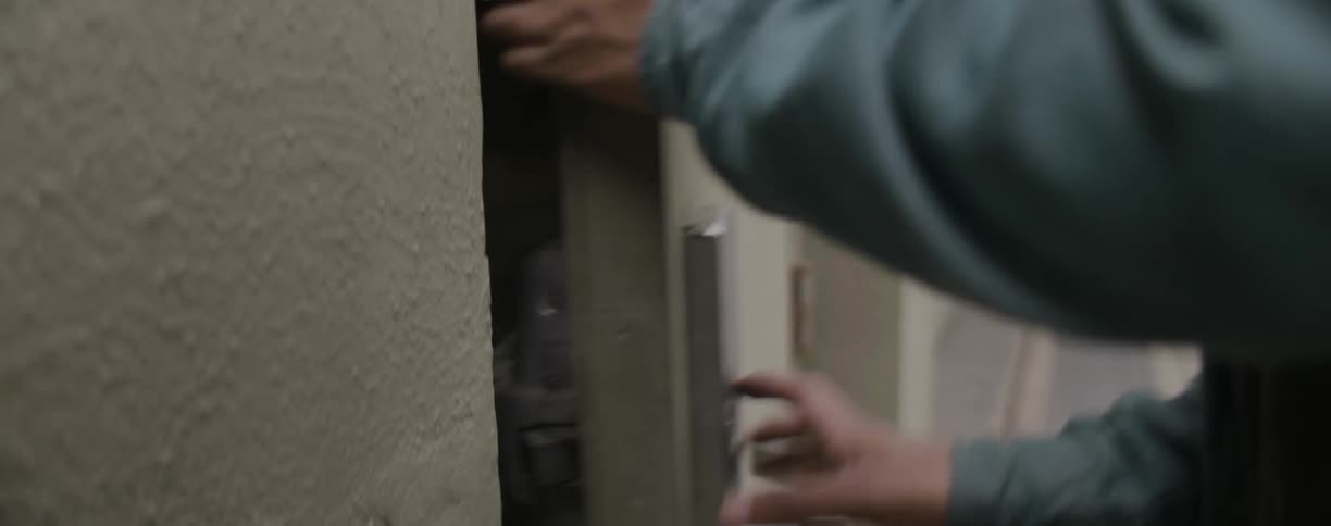 A person walks over to a building and enters through a door