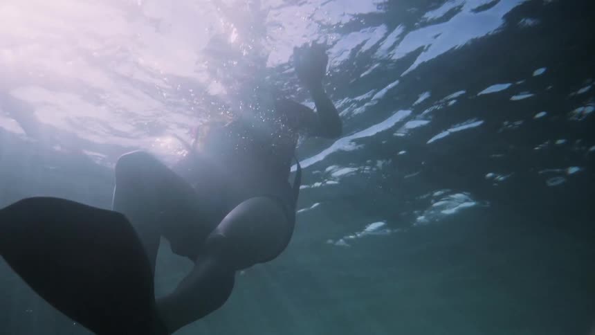 A woman swims in the ocean with flippers