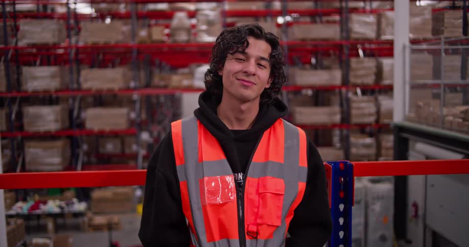 Portrait of a smiling young male warehouse worker standing confidently in a large distribution center