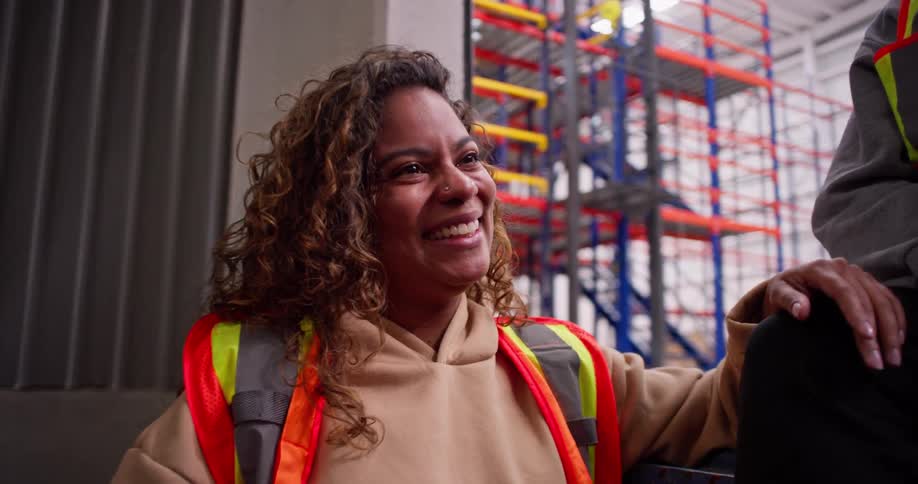 A slow-motion shot captures two diverse female warehouse employees high-fiving in a moment of teamwork and friendship