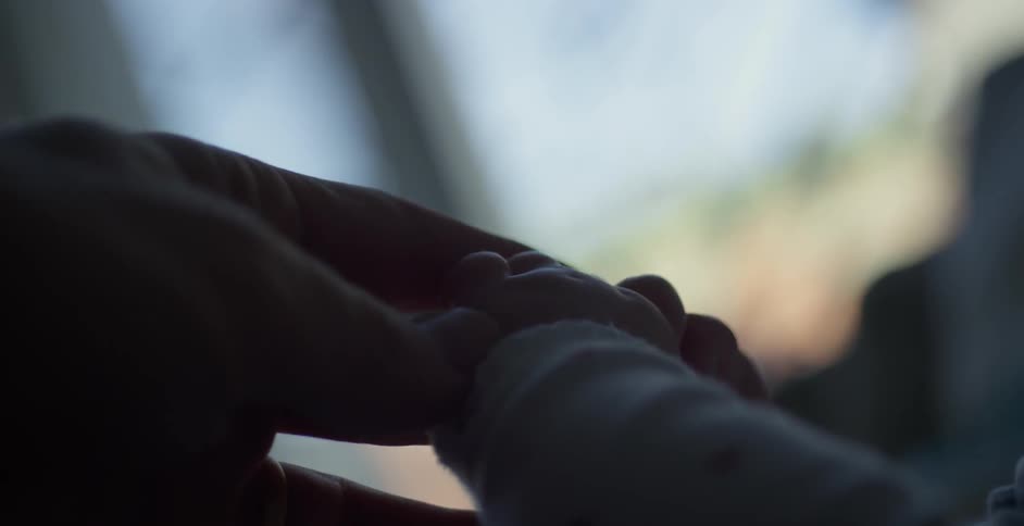 A baby grabs an adults fingers