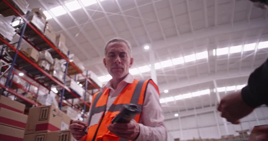 Warehouse employees collaborate to scan, pack, and record inventory in a bustling distribution center