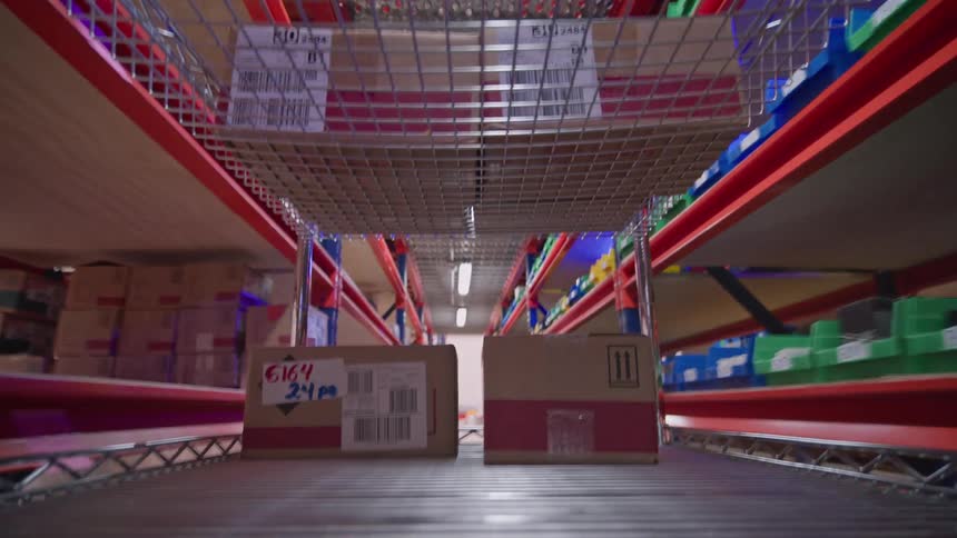 A fast-paced view from a cart traveling down a long aisle in a modern warehouse filled with stocked shelves