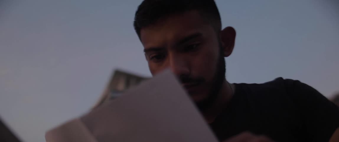Man sits at dusk reading a piece of paper