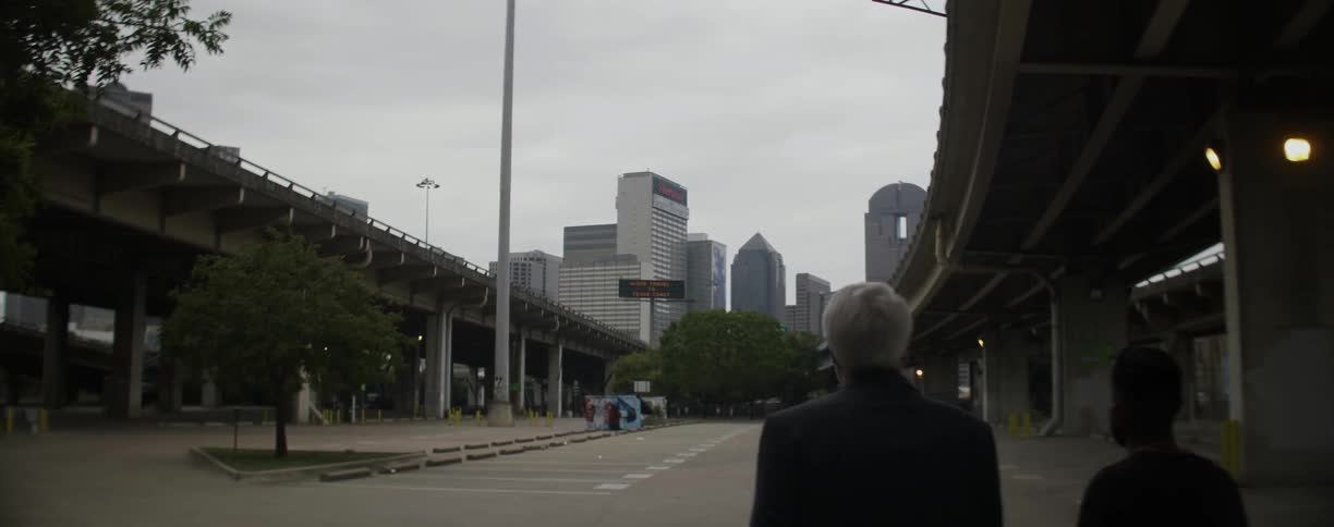 Two men walk in a city parking lot