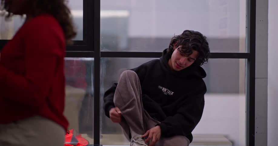 A young man and woman have a friendly conversation in a locker room as they prepare for their day