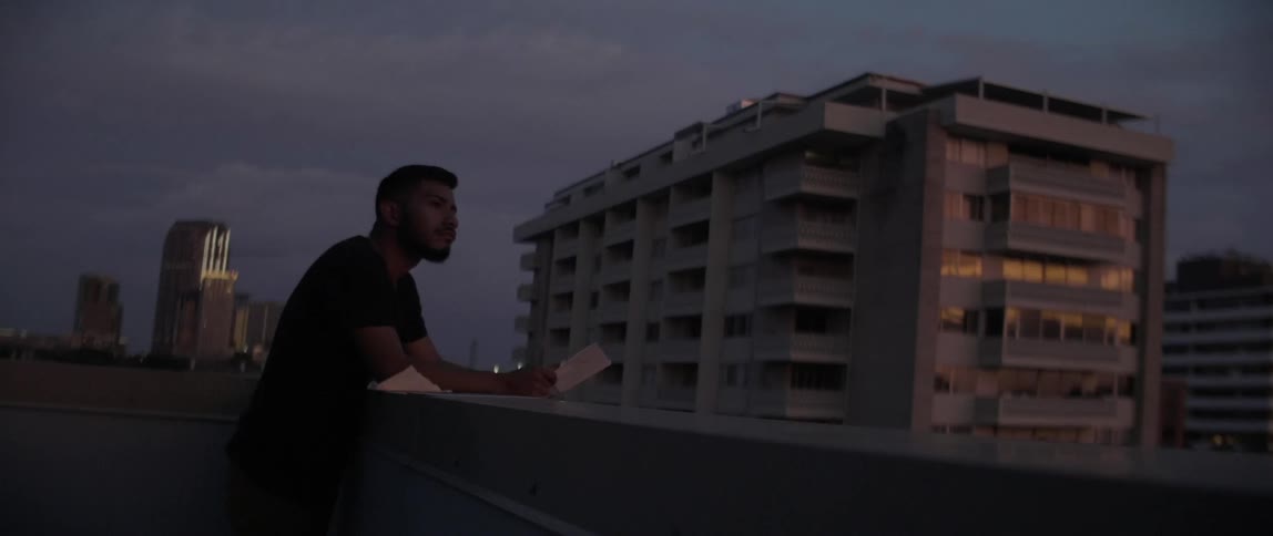 Man standing on a balcony holding a piece of paper