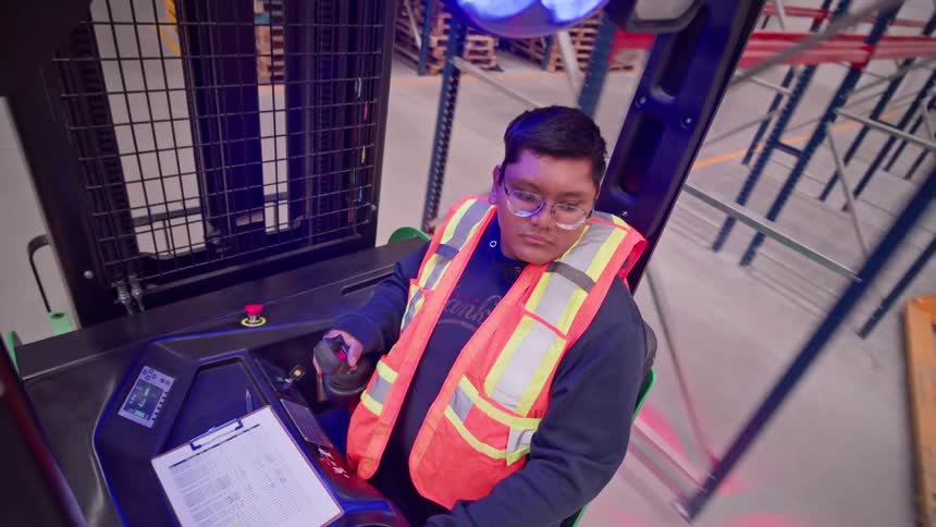 Time-lapse from a forklift operator's point of view as he skillfully maneuvers through a bustling warehouse