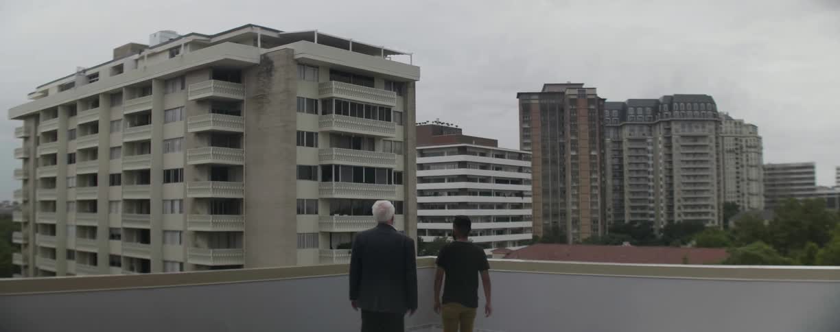 Two men walking to the edge of a balcony
