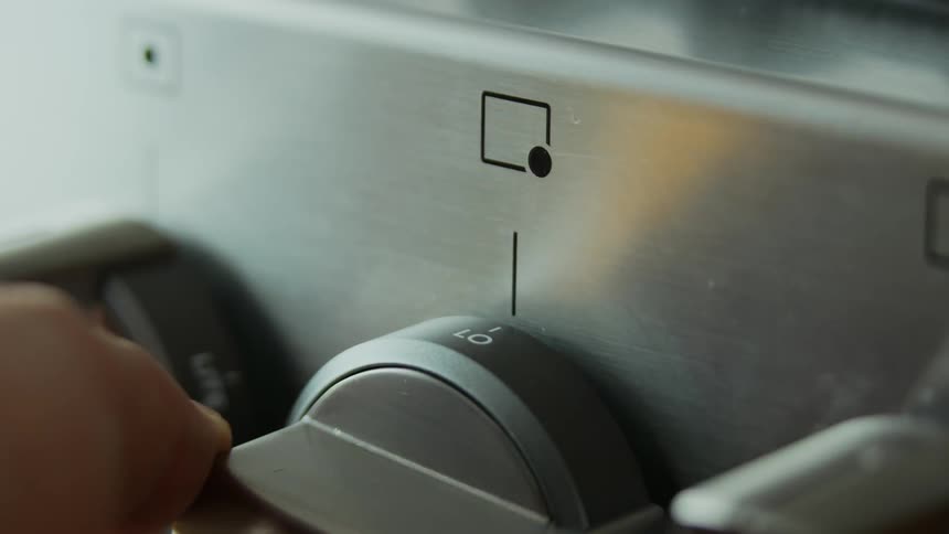 A person turns the dial on a stove