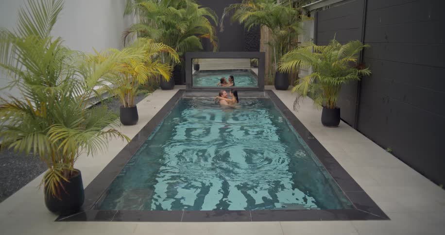 A man dives into a luxurious private pool in slow motion to join his partner for a romantic embrace