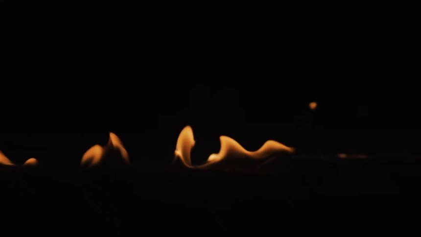 A fire burns in a line in a dark place