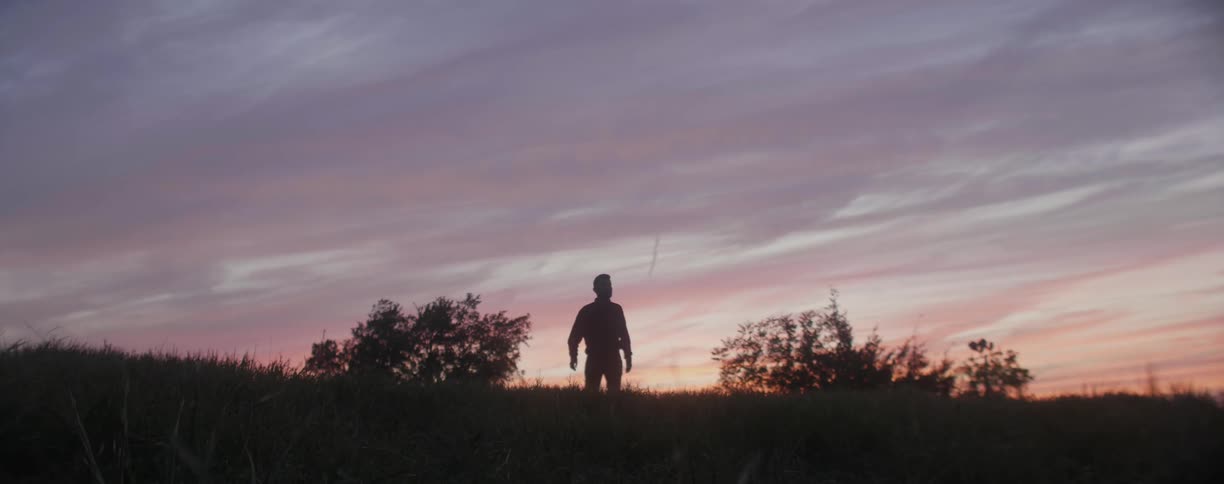 A man walks through the grass at dawn