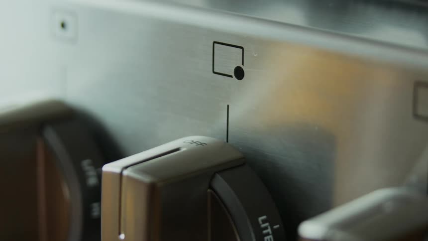 Person turning a knob on a stove
