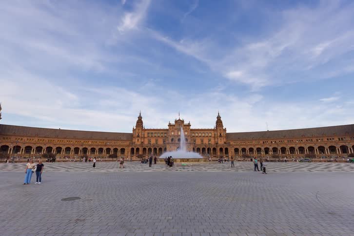A dynamic time-lapse pushes forward through the bustling Plaza de España in Seville, Spain, as tourists explore the grand architecture and central fountain