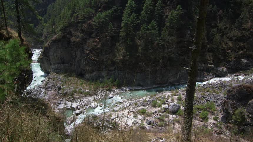 A stream flows at the base of cliffs in a gully