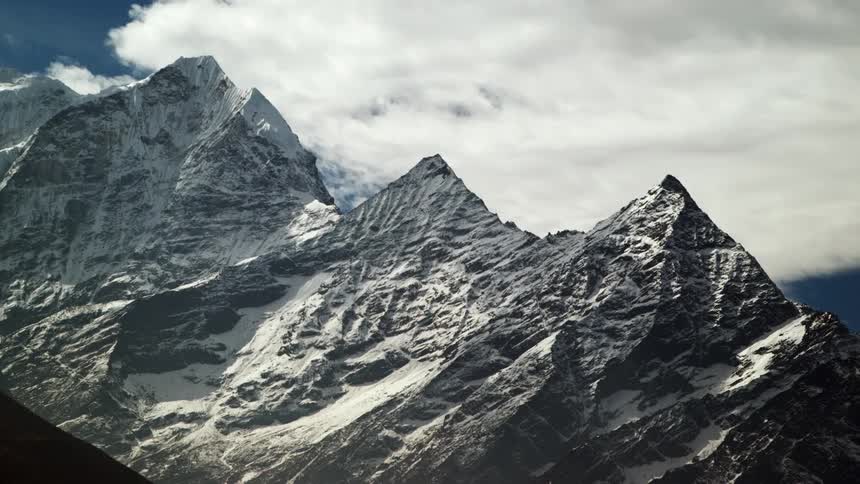 Clouds roll over the peaks of a snow-covered mountain range