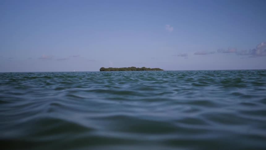 Rippling ocean waters with island in the distance on sunny day
