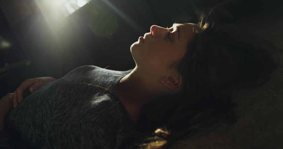 Sun rays shine on woman laying on her bed