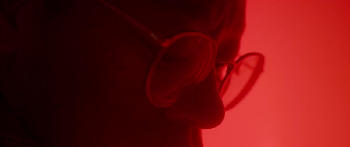 Close up of a person's glasses looking at a red screen