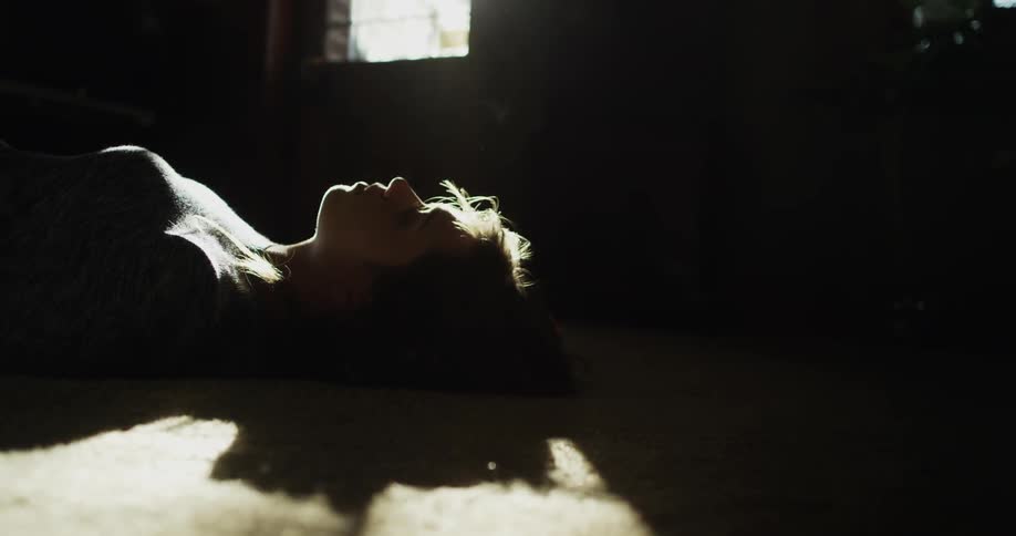 A woman is laying down in a dark room