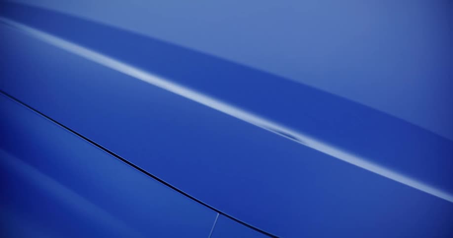An abstract close-up shot highlights the sleek design and body lines of a modern blue automobile